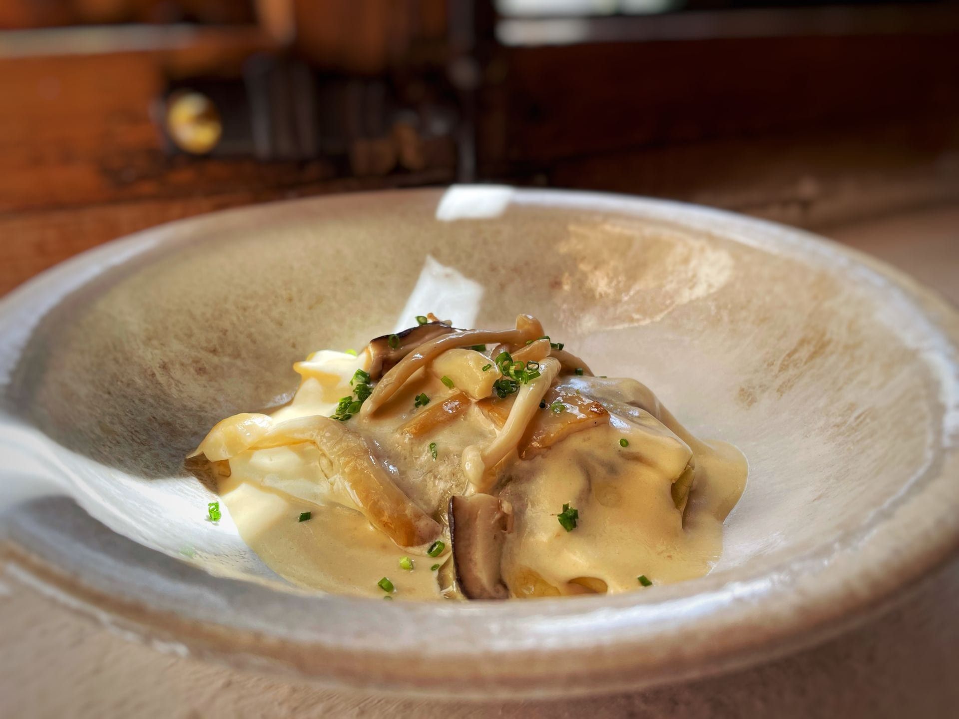 Puré de papas cremoso cubierto con champiñones y cebollino en un recipiente rústico.
