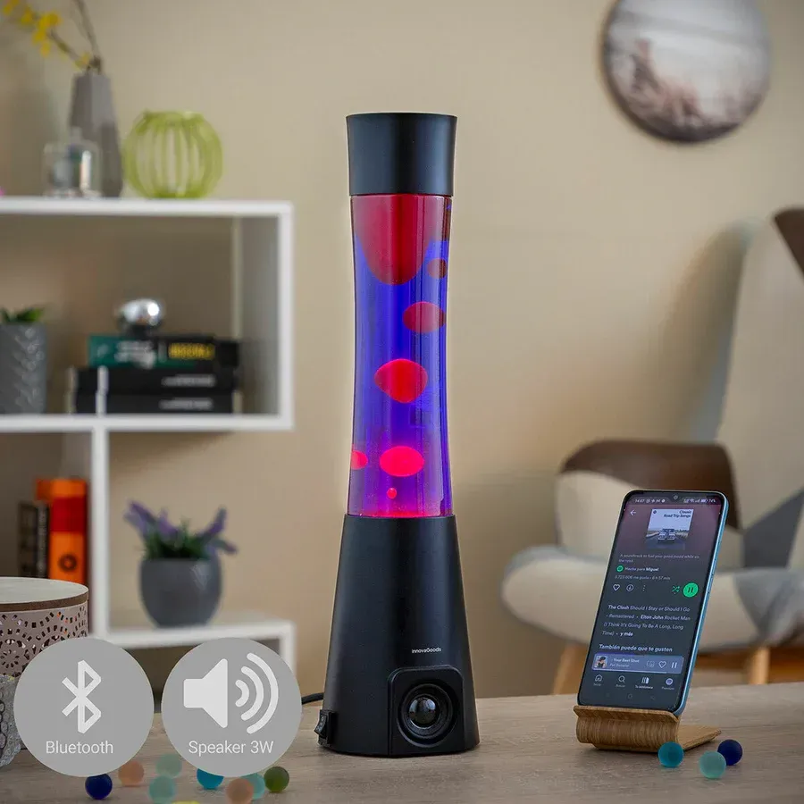 Una lámpara de lava está sobre una mesa junto a un teléfono celular.