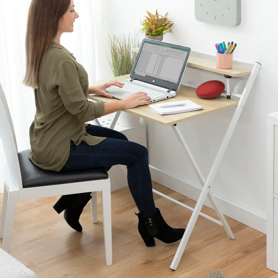 Una mujer está sentada en un escritorio con una computadora portátil encima.