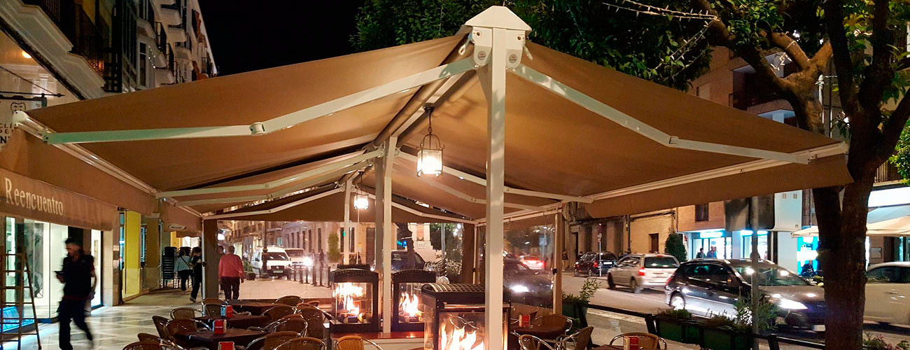 Un restaurante con mesas y sillas bajo un toldo por la noche.