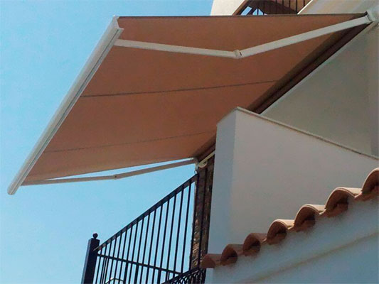 Un balcón con un toldo marrón encima.