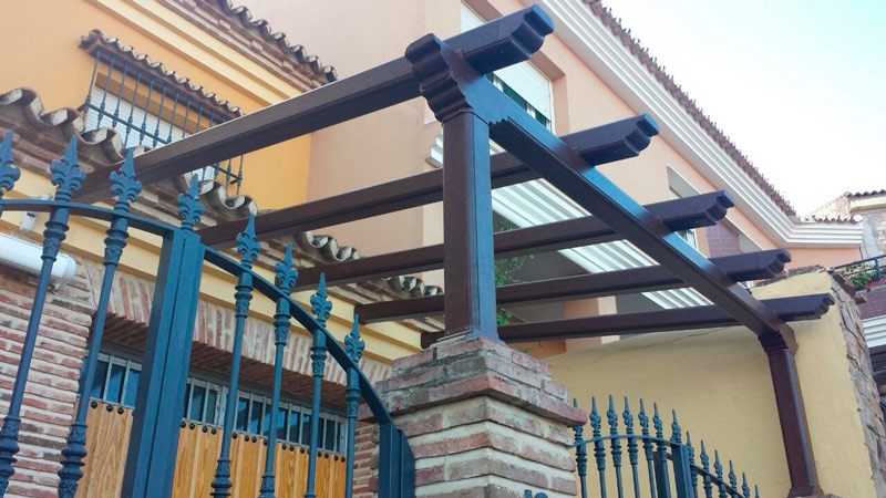 Una pérgola de madera está fijada al costado de un edificio.