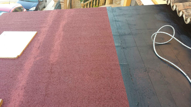 Se está instalando una alfombra roja y negra sobre un techo negro.