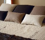 Una cama con una manta y almohadas encima.