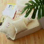 Una pila de almohadas encima de una mesa de madera al lado de una planta.