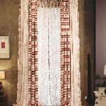 Una sala de estar con una gran ventana con cortinas y una lámpara.