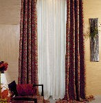 Una sala de estar con cortinas rojas y blancas y una silla.