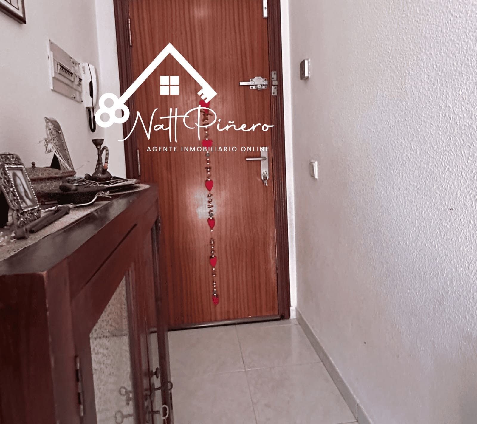 Pasillo con puerta de madera, armario y pared blanca.