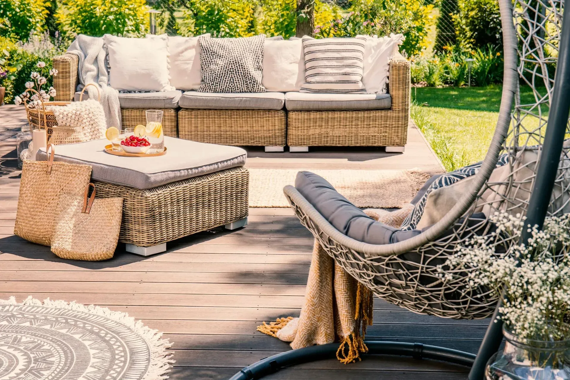 Un patio con muebles de mimbre y una silla colgante.