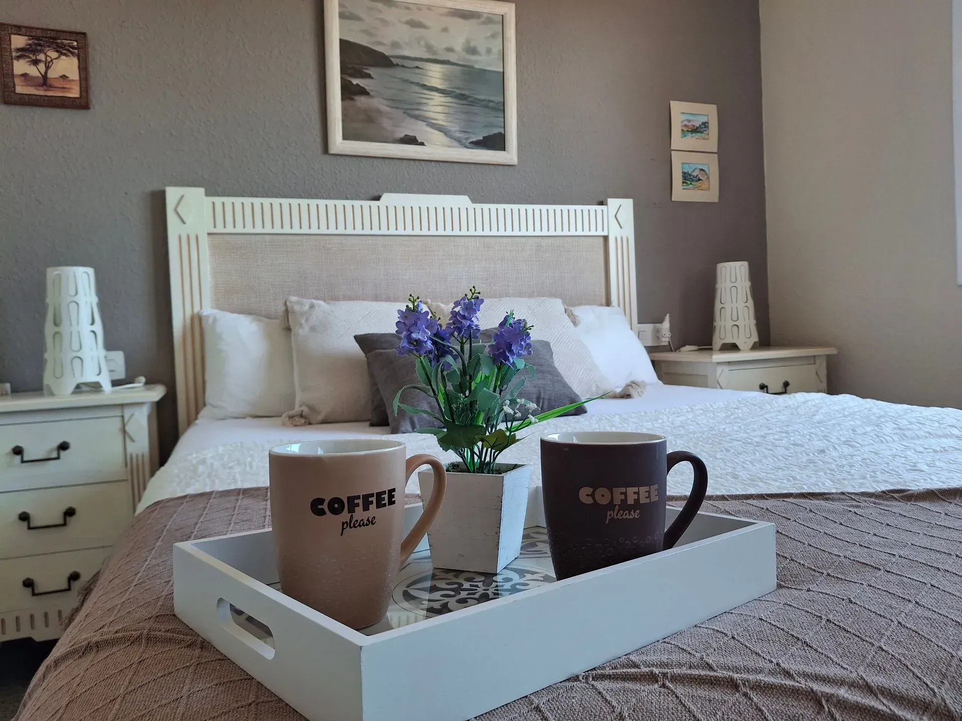 Dos tazas de café están en una bandeja sobre una cama.