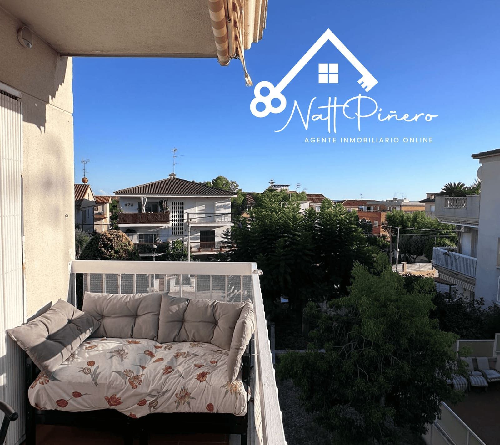 Balcón con banco acolchado, con vista a un barrio soleado.