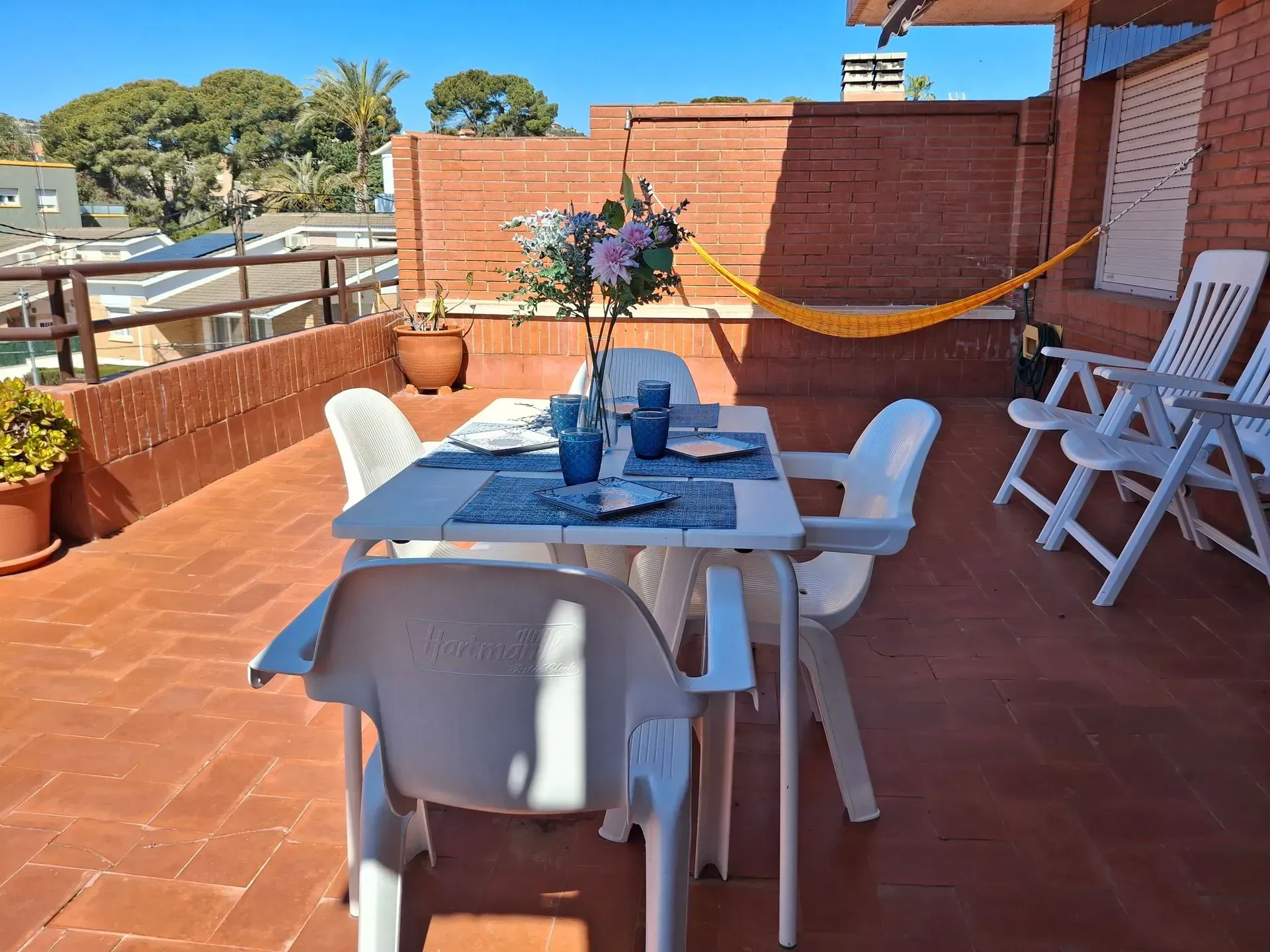 Un patio con mesa y sillas y una hamaca.