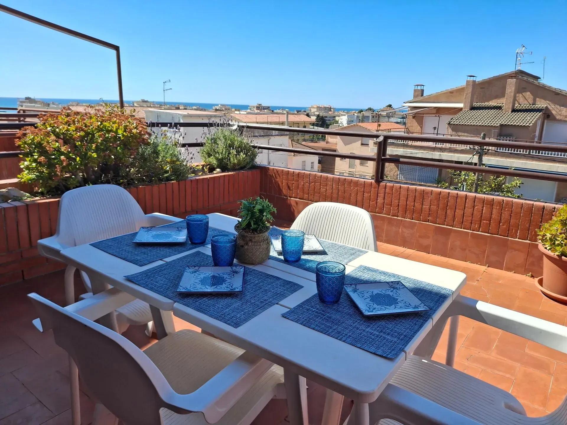 Una mesa y sillas en un balcón con vista al mar.