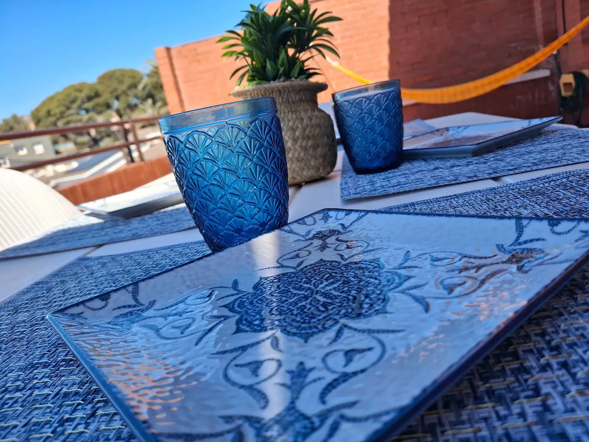 Dos vasos azules están sobre un plato azul y blanco sobre una mesa.