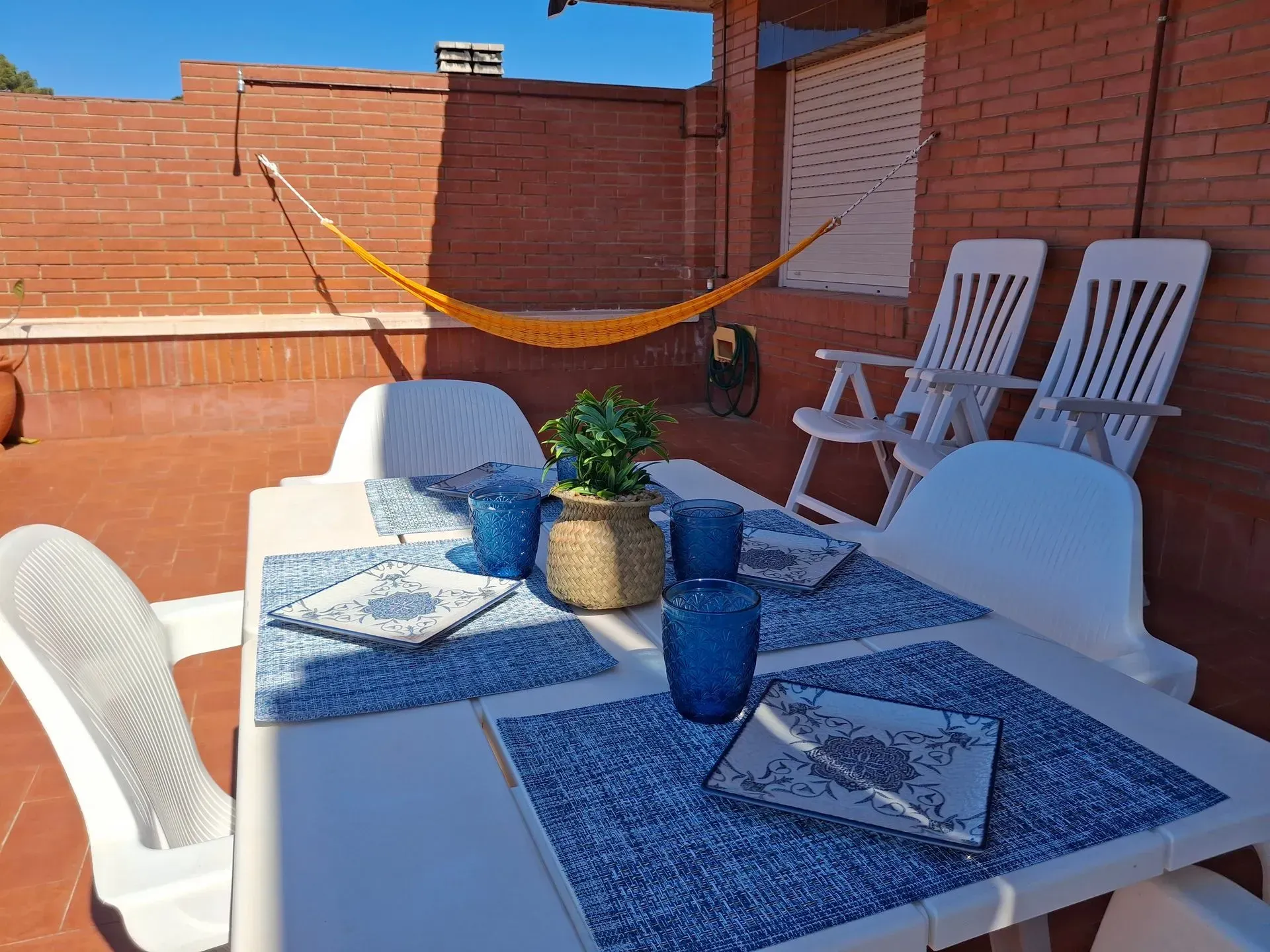 Un patio con mesa y sillas y una hamaca.