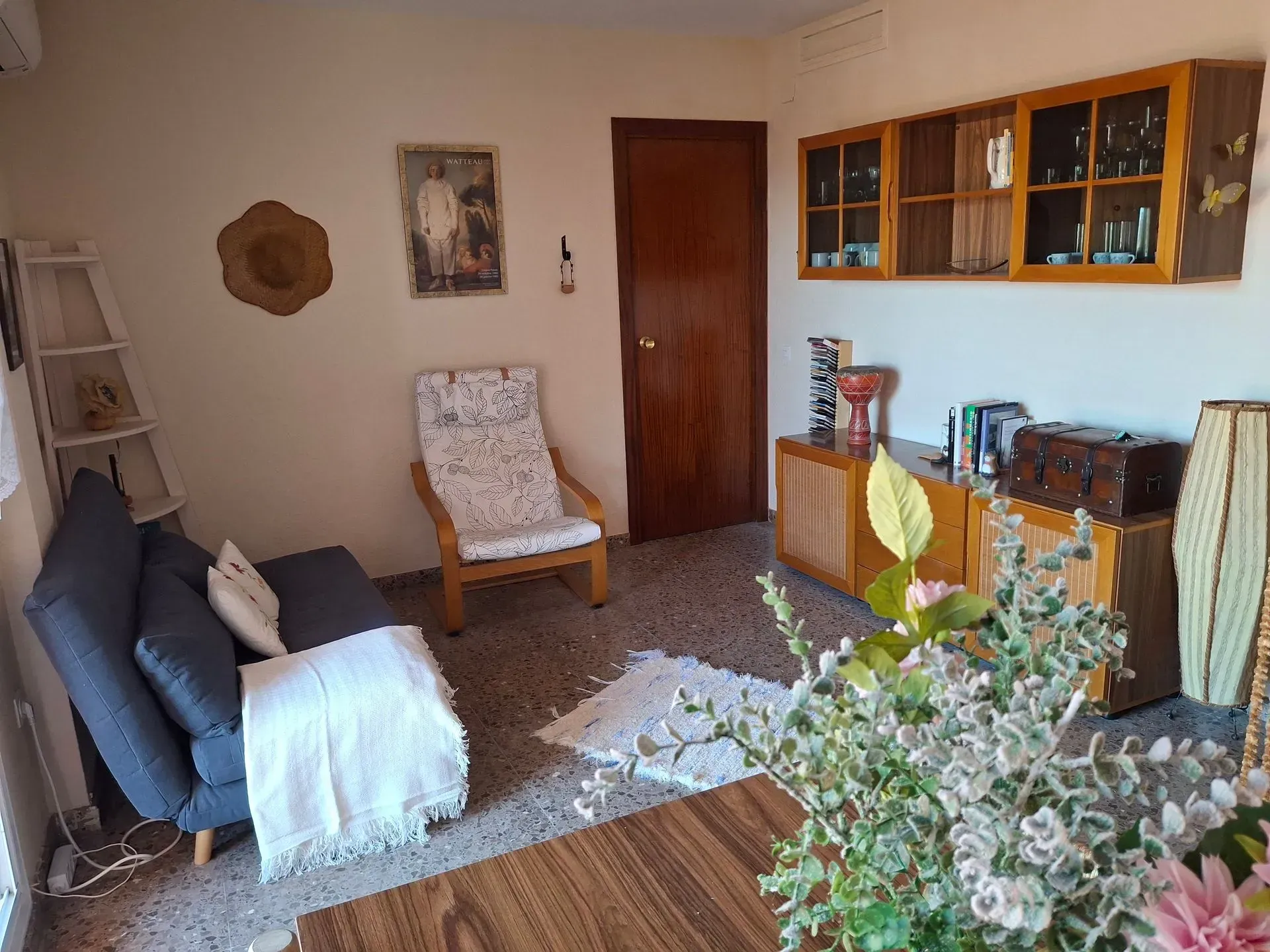 Una sala de estar con un sofá, una silla, una mesa y flores.