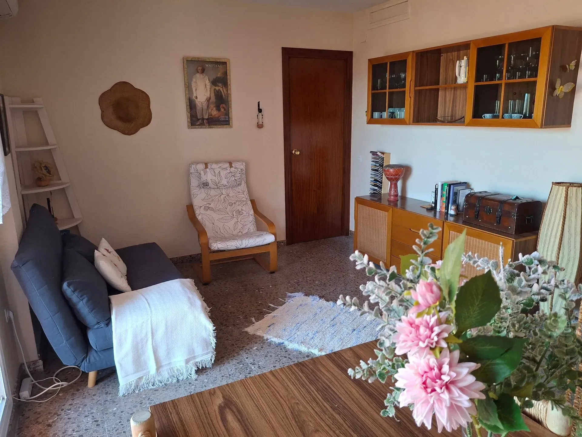 Una sala de estar con un sofá, una silla, una mesa y flores.