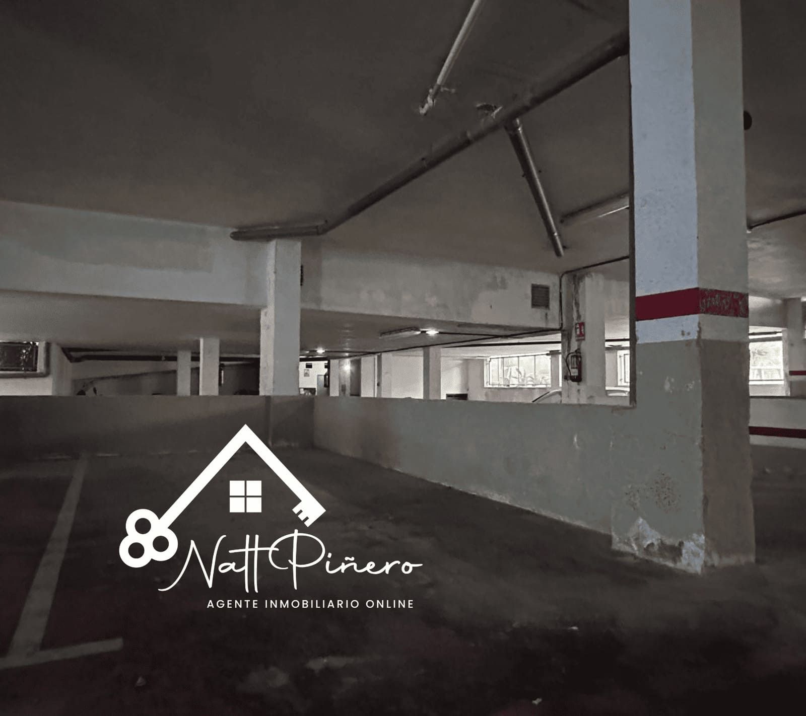 Aparcamiento cubierto vacío con pilares de hormigón y rampa.