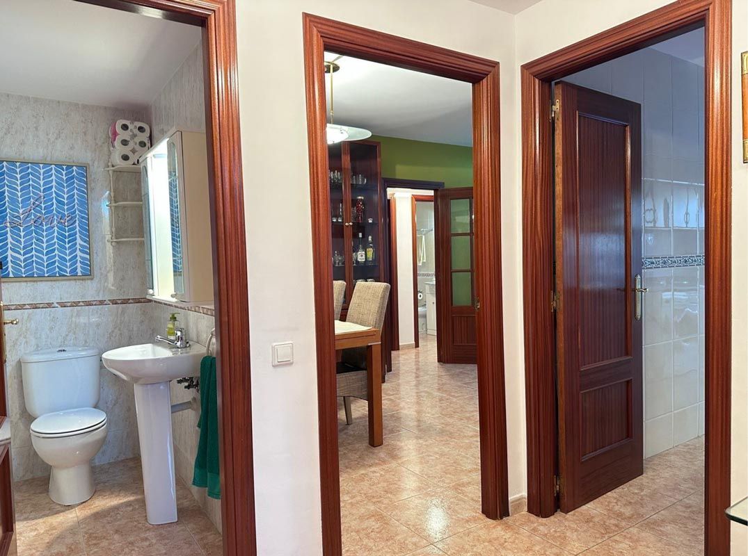 Pasillo con tres puertas de madera: baño, comedor y otra habitación.