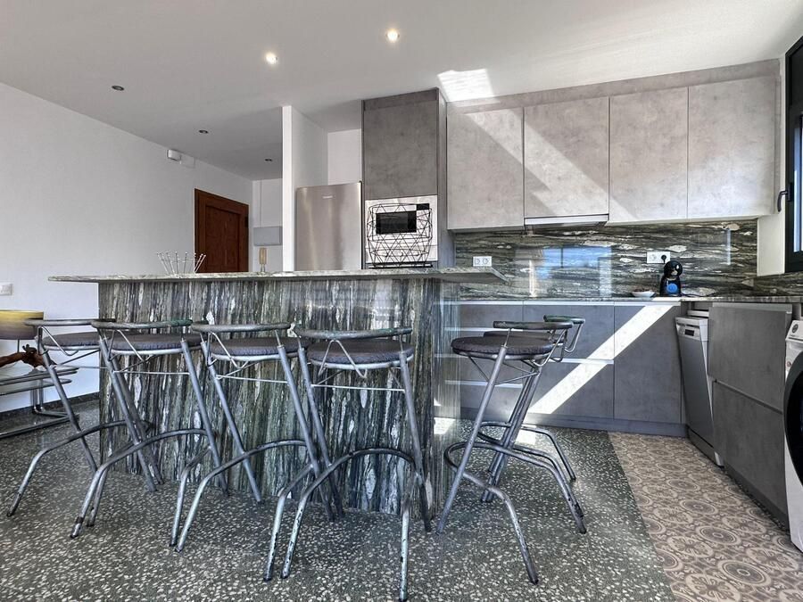 Cocina moderna con isla con asientos, electrodomésticos de acero inoxidable y pisos moteados.