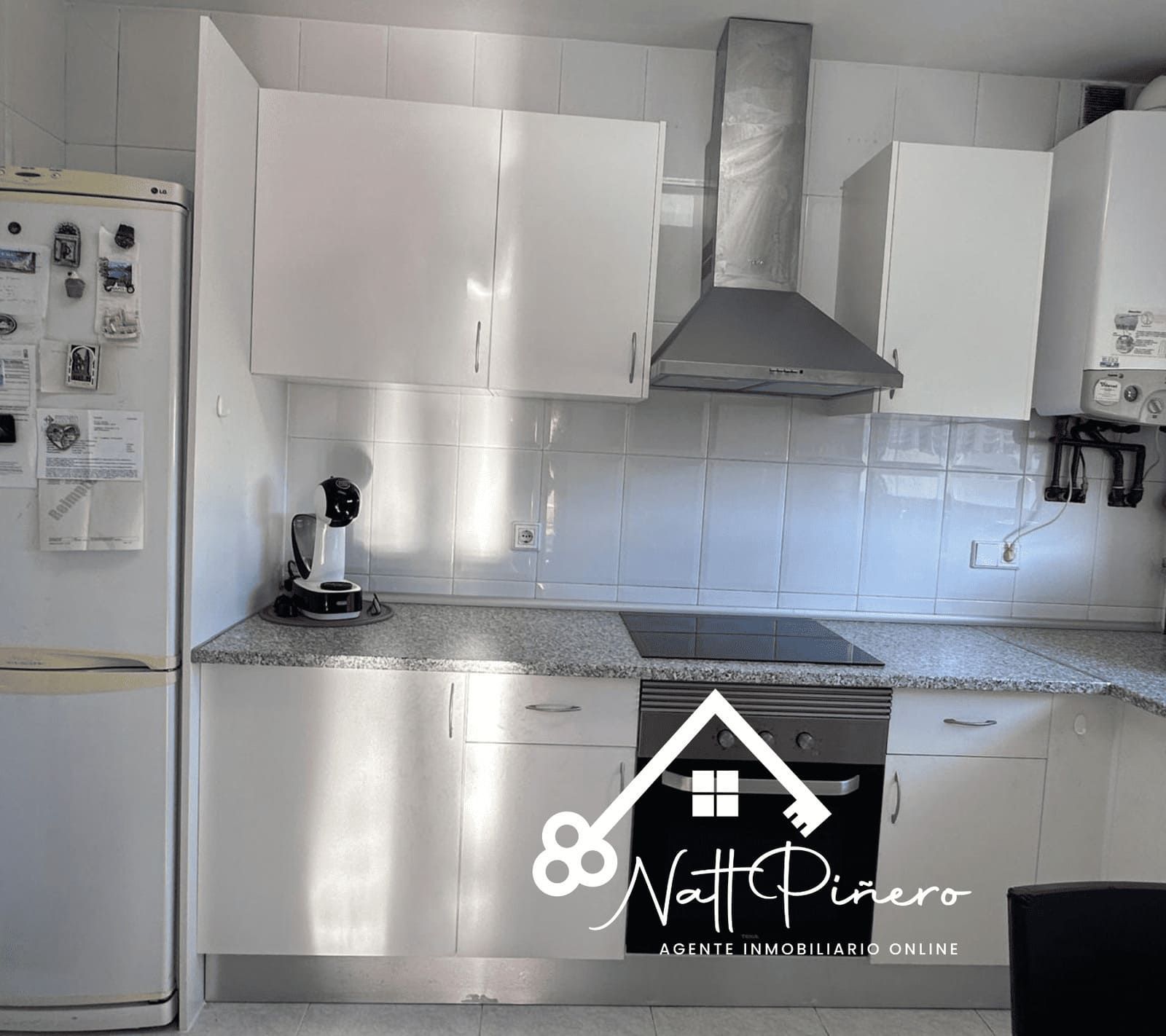 Gabinetes de cocina blancos, electrodomésticos de acero inoxidable, encimeras de granito.