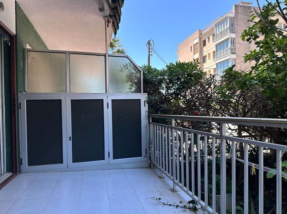 Un balcón con barandilla de metal y puerta de cristal.