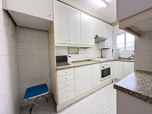 Una cocina con gabinetes blancos y encimeras de granito.