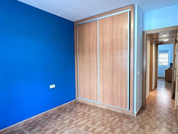 Un dormitorio con paredes azules y un armario de madera.
