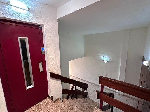 Una escalera con una puerta roja y una barandilla de madera.