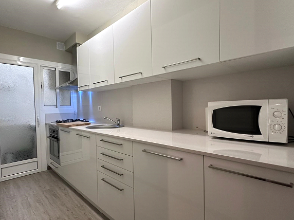 Una cocina con gabinetes blancos y un microondas en el mostrador.