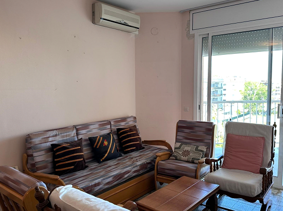 Una sala de estar con sofá, silla, mesa de café y aire acondicionado.