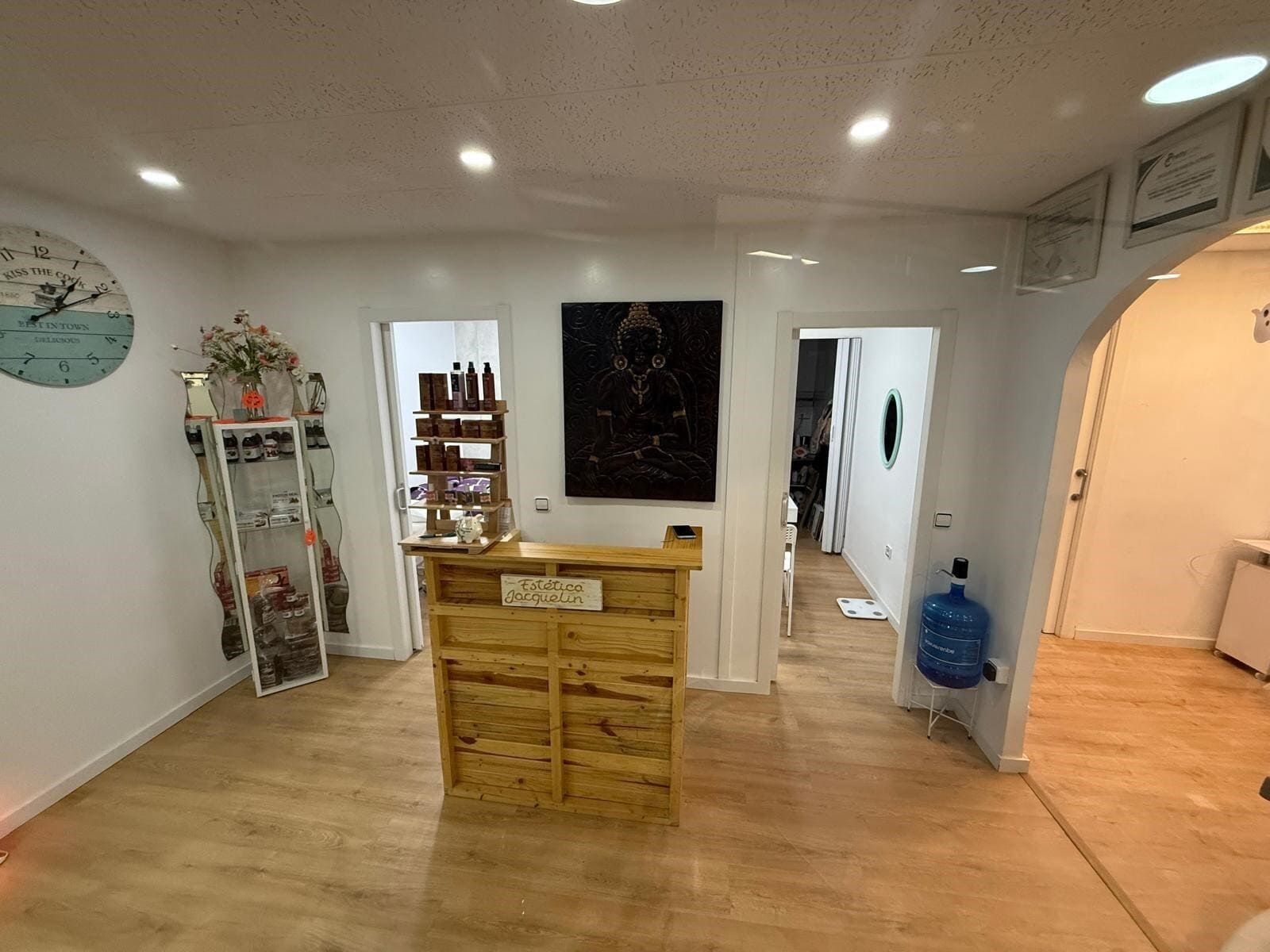 Área de recepción con mostrador de madera, dos puertas y dispensador de agua.