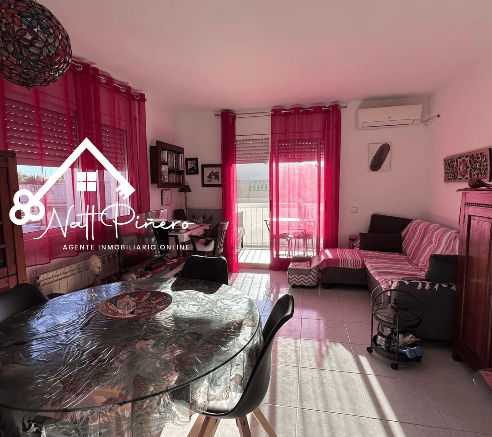 Sala de estar con comedor y acceso al balcón, cuenta con mesa, sillas, sofá y cortinas rojas.