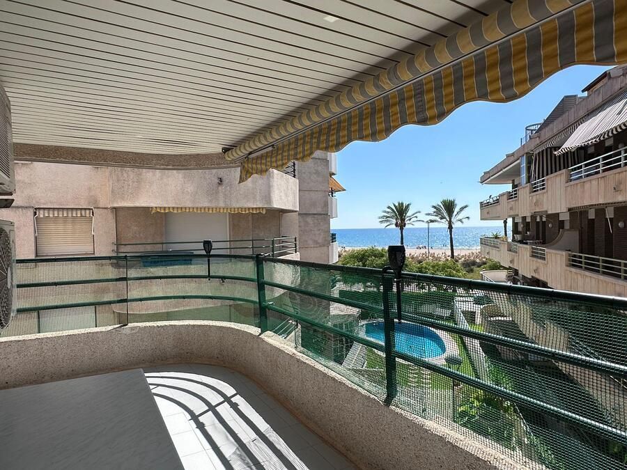 Vista desde el balcón del océano, la piscina y los edificios en un día soleado.