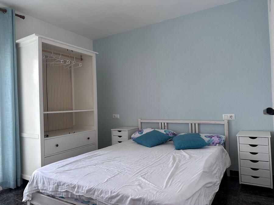 Dormitorio con armario blanco, cama con almohadas azules y pared azul.