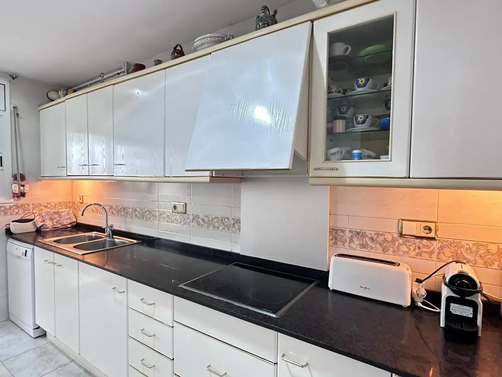 Una cocina con gabinetes blancos y encimeras negras.