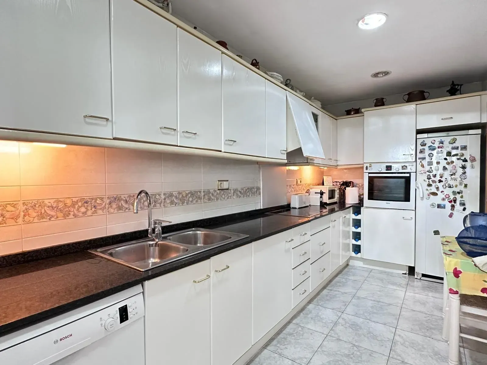 Una cocina con gabinetes blancos y encimeras negras.