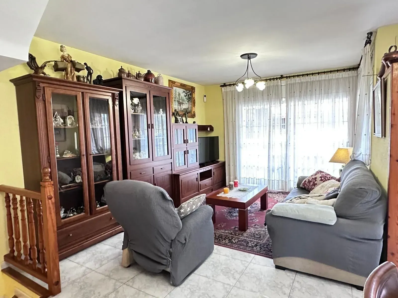 Una sala de estar con un sofá, sillas y un televisor.