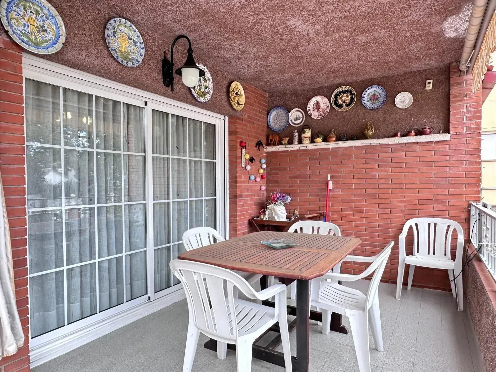 Un patio con mesa y sillas y platos en la pared.