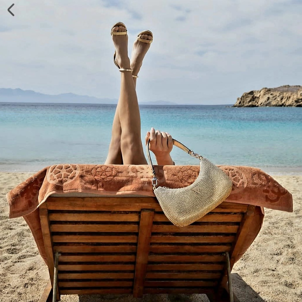 Una mujer está acostada en una silla de playa con las piernas levantadas.