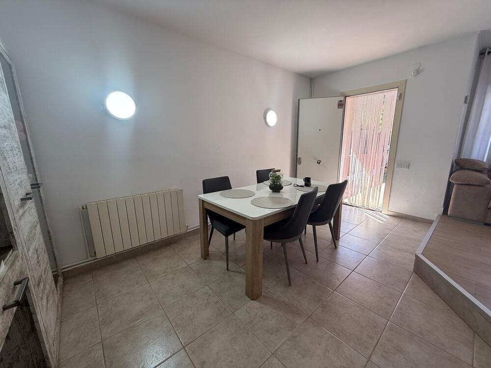 Comedor con mesa, sillas, radiador y puerta abierta al exterior.