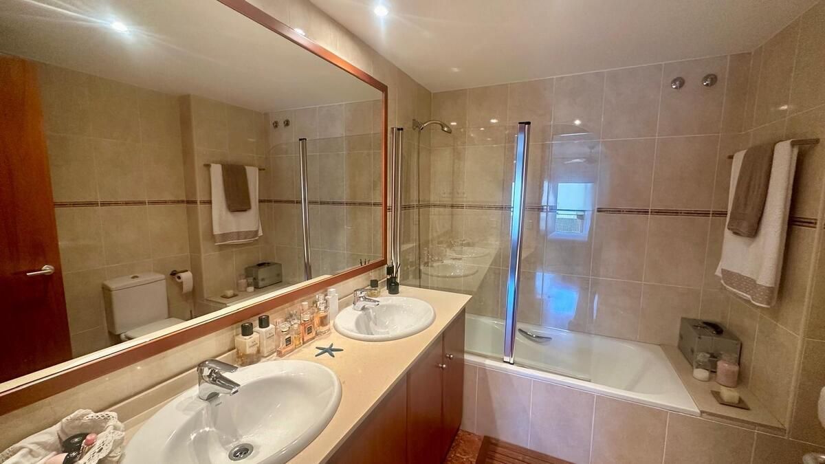 Un baño con dos lavabos, una bañera y un espejo.