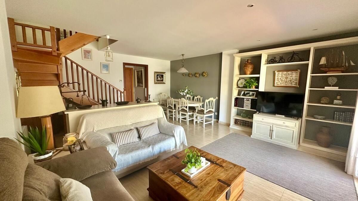 Una sala de estar con sofá, mesa y escaleras.