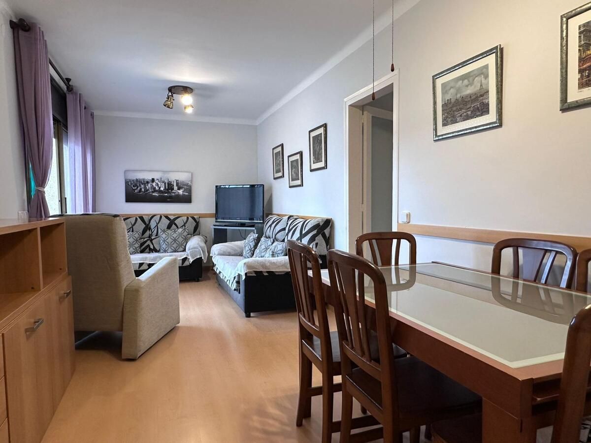 Sala de estar con mesa de comedor y sillas de madera, sofás, obras de arte y armarios.