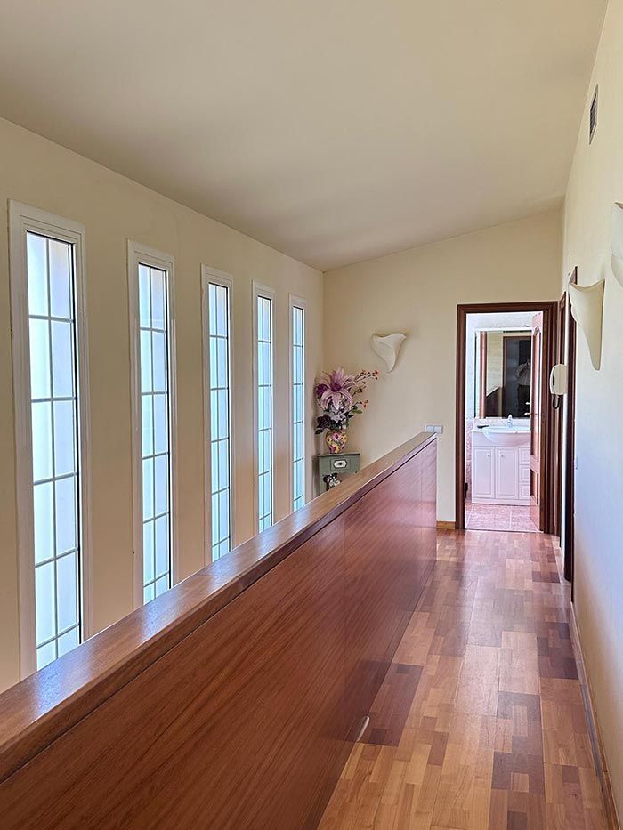 Un largo pasillo con pisos de madera y muchas ventanas.