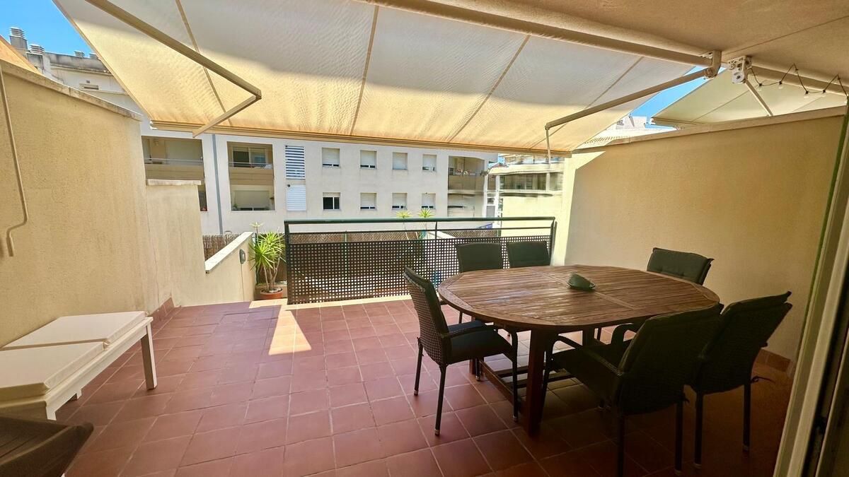 Un patio con una mesa y sillas bajo un toldo.