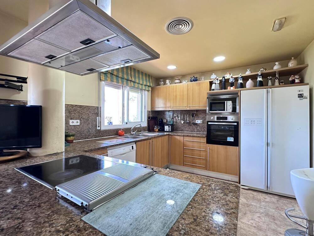 Una cocina con horno, refrigerador, lavavajillas, microondas y televisión.