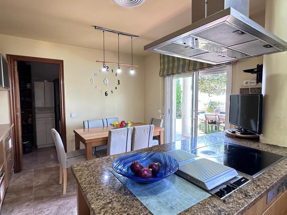 Una cocina con una mesa y sillas y un bol de fruta en la encimera.