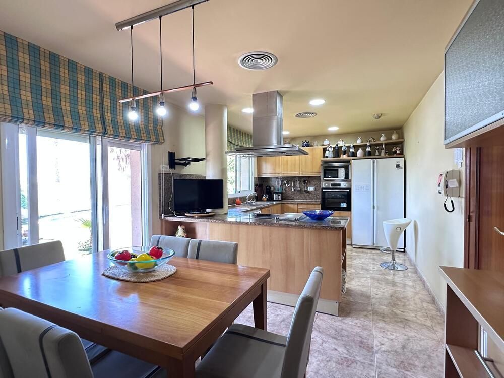 Un comedor con una mesa y sillas y una cocina al fondo.