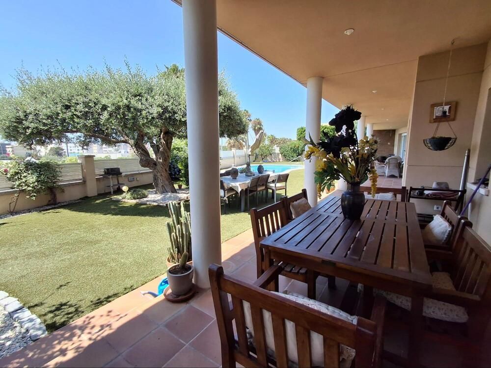 Un patio con una mesa y sillas y un jarrón de flores.